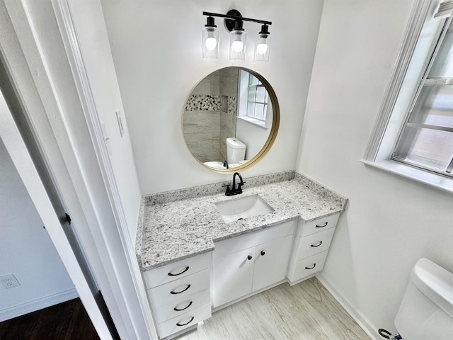 half bathroom with baseboards, toilet, and vanity