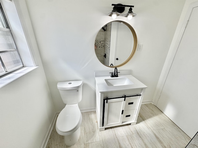 bathroom with vanity, toilet, wood finished floors, and baseboards