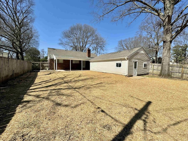 back of house with a fenced backyard and a chimney