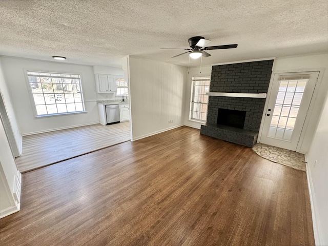 unfurnished living room with a wealth of natural light, a brick fireplace, and wood finished floors