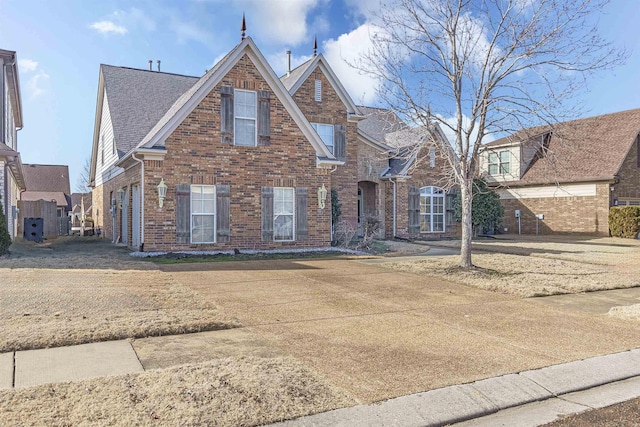 view of front of property featuring brick siding and roof with shingles