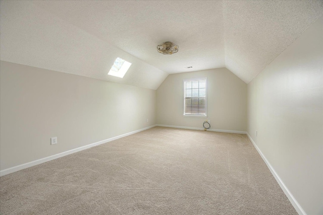 bonus room featuring light colored carpet, a textured ceiling, baseboards, and vaulted ceiling