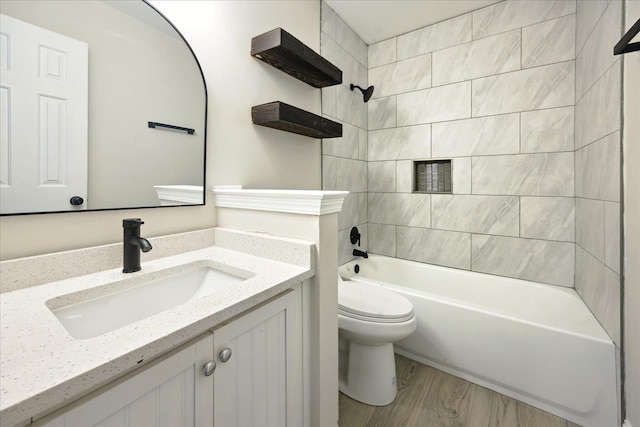 full bathroom featuring bathing tub / shower combination, toilet, wood finished floors, and vanity