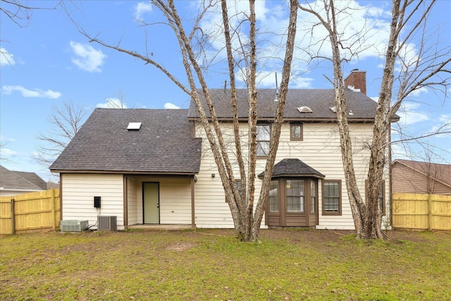 rear view of house featuring a yard, fence, and a chimney