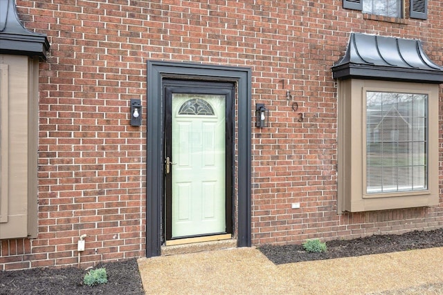 entrance to property with brick siding, metal roof, and a standing seam roof