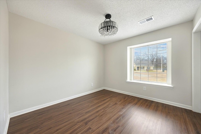 unfurnished room with dark wood-style floors, visible vents, a textured ceiling, and baseboards