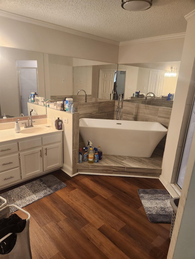 bathroom featuring crown molding, a freestanding bath, wood finished floors, a textured ceiling, and vanity