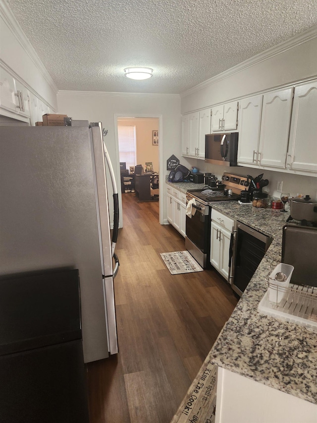 kitchen featuring dark wood-type flooring, light stone countertops, ornamental molding, white cabinets, and stainless steel appliances