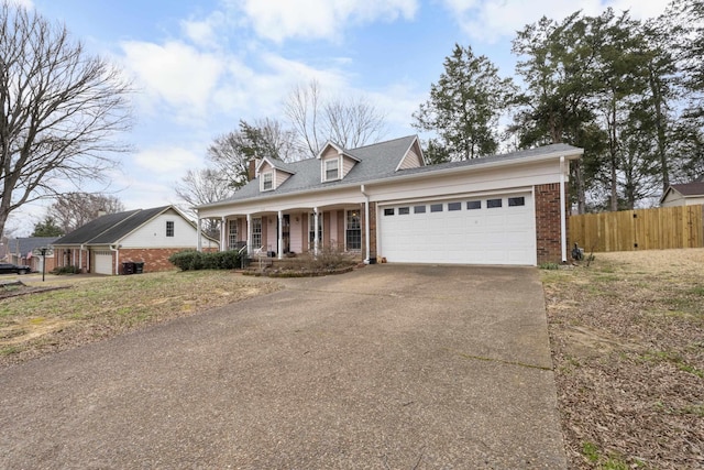 new england style home with fence, driveway, a porch, an attached garage, and brick siding