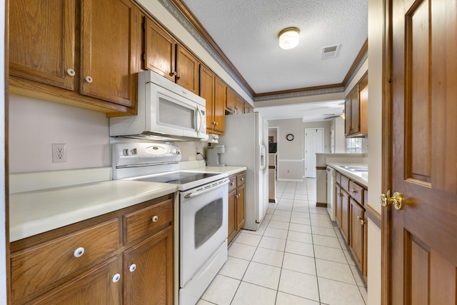 kitchen featuring visible vents, white appliances, brown cabinetry, light countertops, and crown molding