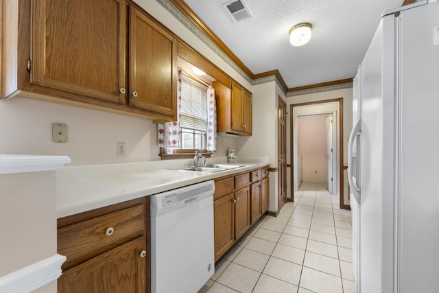 kitchen with visible vents, light tile patterned floors, brown cabinetry, white appliances, and a sink