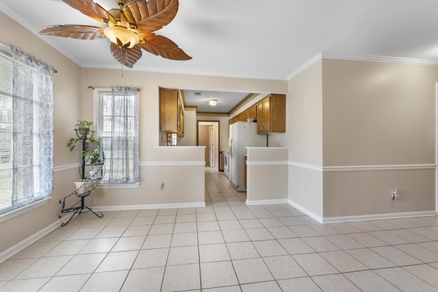 empty room with light tile patterned floors, baseboards, ornamental molding, and ceiling fan