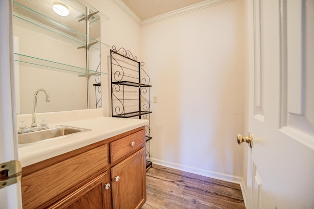 washroom with a sink, baseboards, light wood-style floors, and ornamental molding