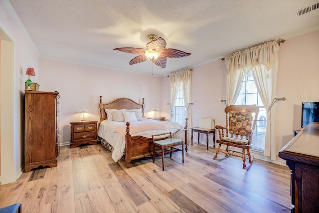 bedroom with light wood-type flooring, visible vents, a textured ceiling, and crown molding