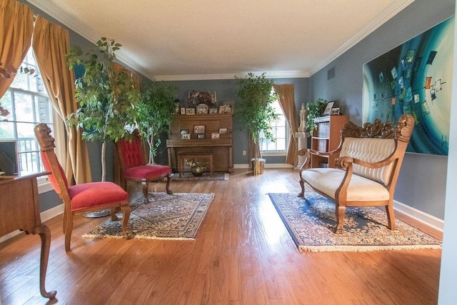 living area featuring visible vents, crown molding, baseboards, a fireplace, and wood finished floors