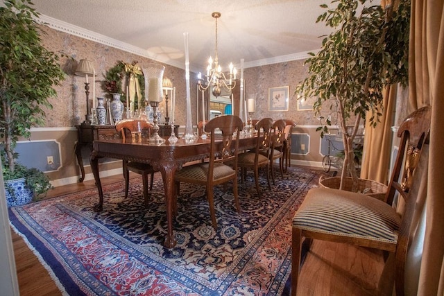 dining room with wallpapered walls, a wainscoted wall, ornamental molding, an inviting chandelier, and a textured ceiling