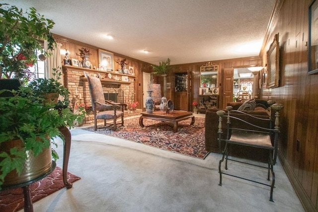 living room with a brick fireplace, wooden walls, carpet, and a textured ceiling