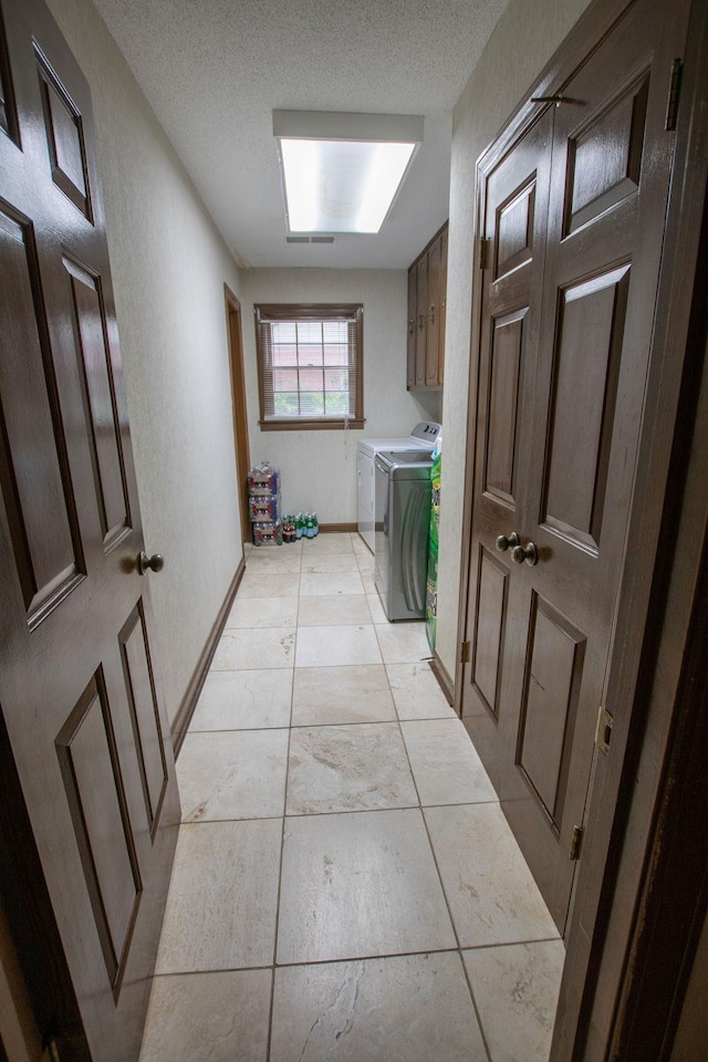 hall with washer and dryer, baseboards, a textured ceiling, and a textured wall