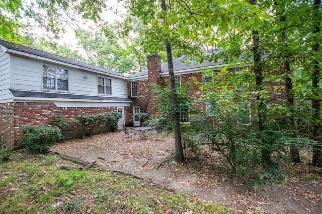 exterior space with brick siding and a chimney