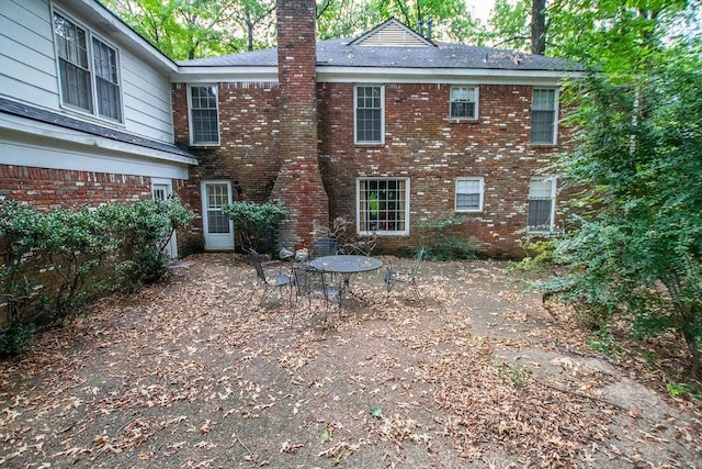 back of property with brick siding and a chimney