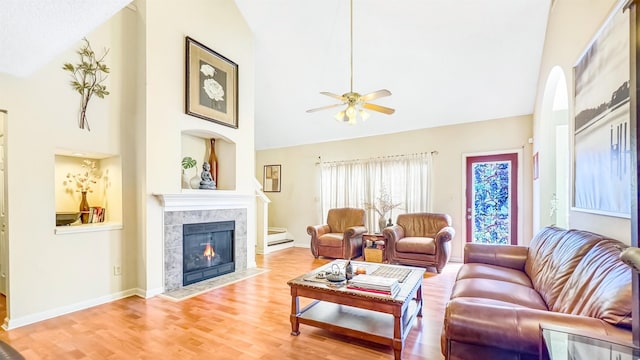 living room featuring baseboards, ceiling fan, a fireplace, wood finished floors, and high vaulted ceiling