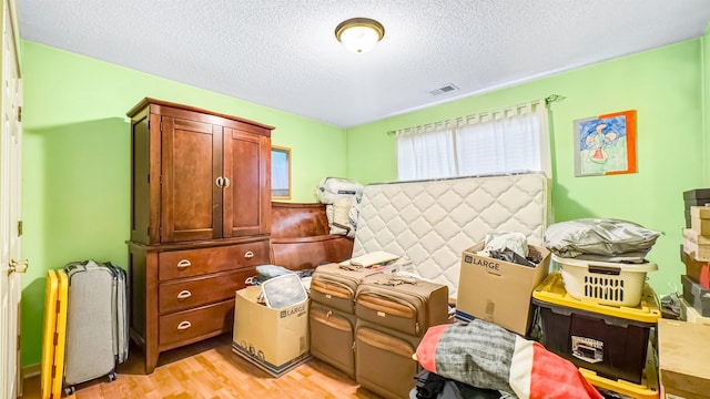 bedroom featuring visible vents, light wood-style floors, and a textured ceiling