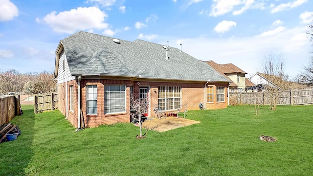 back of property with a fenced backyard, a lawn, brick siding, and roof with shingles