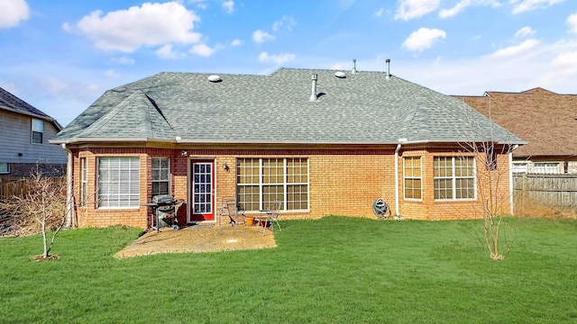 rear view of house with brick siding, a lawn, a shingled roof, and fence