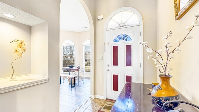 entrance foyer featuring arched walkways and a textured ceiling