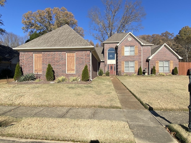 traditional-style home featuring brick siding, roof with shingles, and a front yard