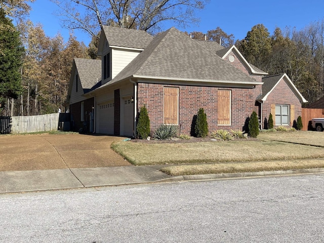 view of property exterior with driveway, fence, an attached garage, a shingled roof, and brick siding