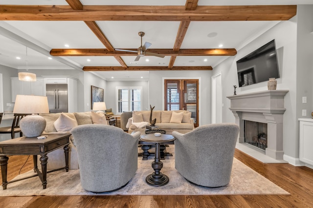 living area with a ceiling fan, wood finished floors, coffered ceiling, beam ceiling, and a fireplace with raised hearth