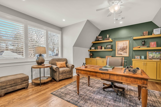 home office with visible vents, light wood-style floors, baseboards, ceiling fan, and vaulted ceiling