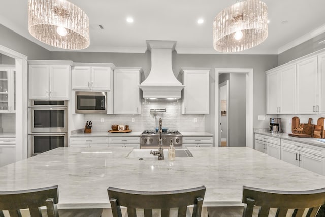 kitchen with white cabinetry, premium range hood, appliances with stainless steel finishes, and ornamental molding