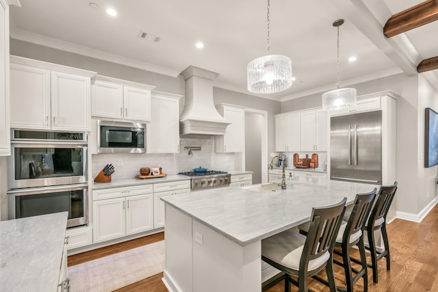 kitchen featuring built in appliances, decorative backsplash, light wood-style floors, custom exhaust hood, and a sink