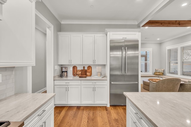 kitchen featuring crown molding, decorative backsplash, light wood-style floors, white cabinetry, and built in fridge