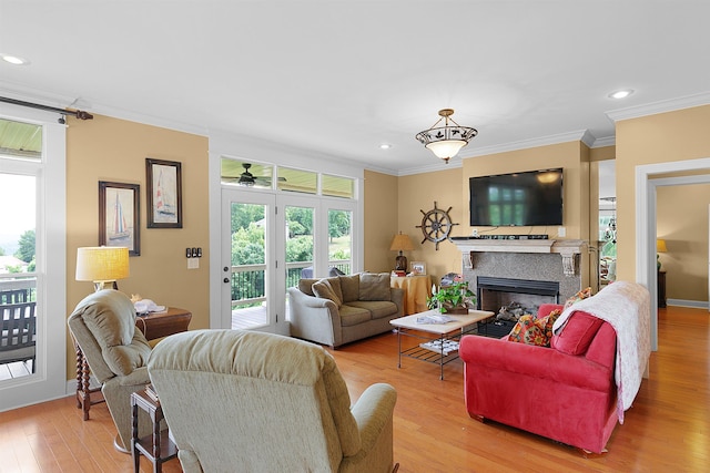 living room featuring recessed lighting, a glass covered fireplace, light wood-style flooring, and crown molding