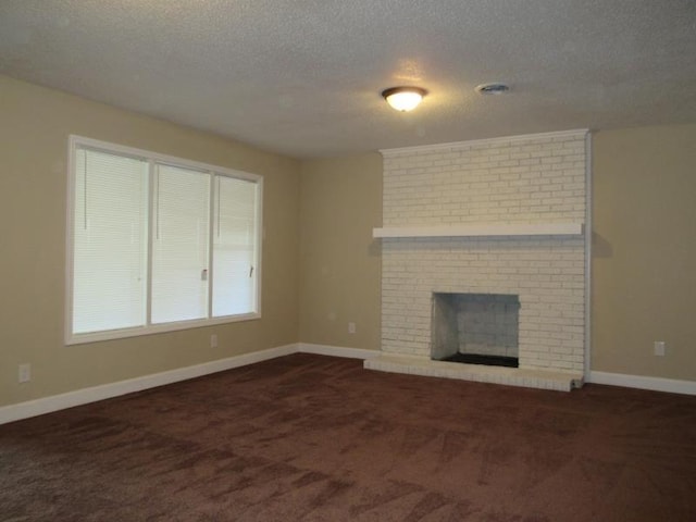 unfurnished living room with dark colored carpet, baseboards, a textured ceiling, and a brick fireplace