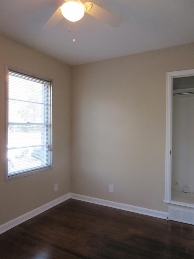 empty room with ceiling fan, baseboards, and dark wood-style flooring