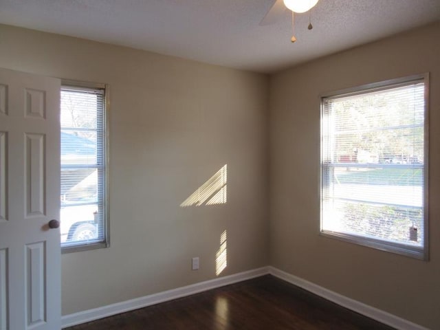 unfurnished room with baseboards, a ceiling fan, a healthy amount of sunlight, and dark wood-style flooring