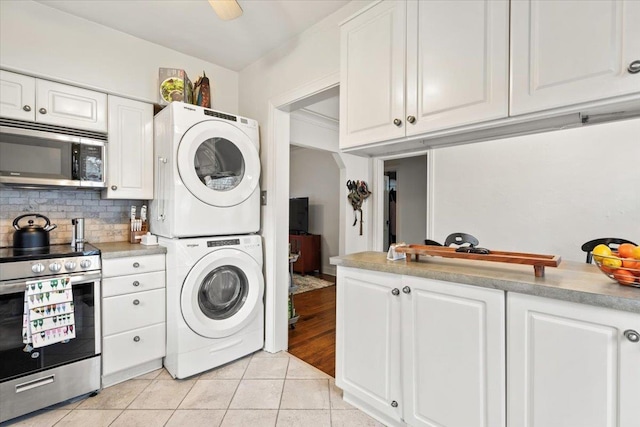 laundry area with laundry area, light tile patterned flooring, and stacked washer / drying machine