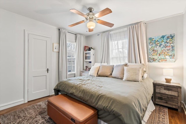 bedroom with multiple windows, dark wood-type flooring, and a ceiling fan