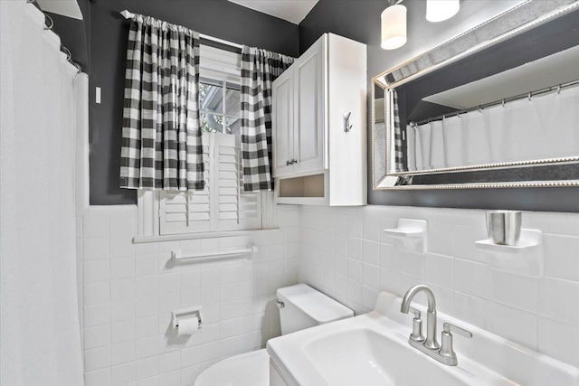 bathroom featuring tile walls, toilet, and a sink