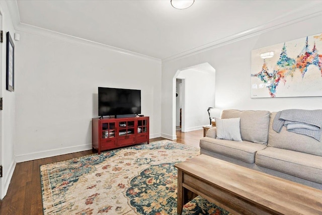 living area with baseboards, wood finished floors, arched walkways, and ornamental molding