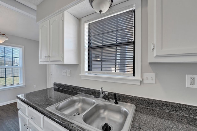 kitchen featuring dark countertops, white cabinetry, and a sink