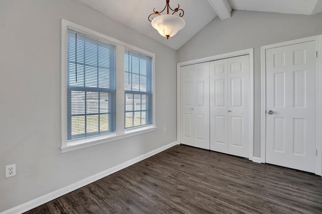 unfurnished bedroom with lofted ceiling with beams, a closet, baseboards, and dark wood-type flooring