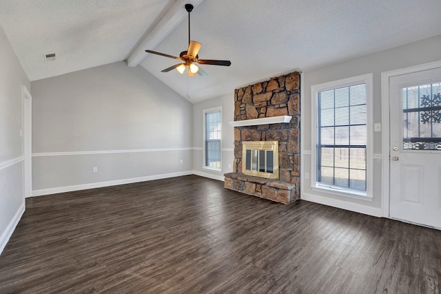 unfurnished living room with visible vents, plenty of natural light, dark wood finished floors, a fireplace, and vaulted ceiling with beams