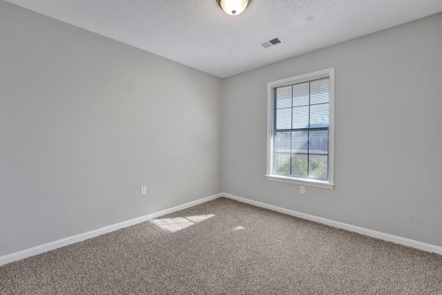 spare room featuring visible vents, a textured ceiling, baseboards, and carpet