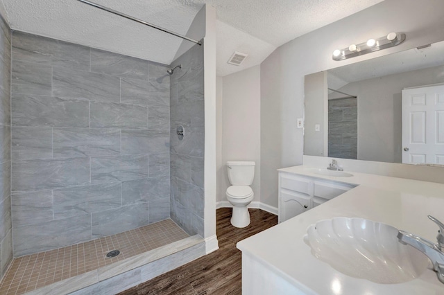 full bathroom with visible vents, tiled shower, toilet, and a sink