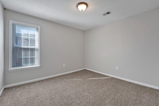 carpeted spare room featuring baseboards, visible vents, and a textured ceiling